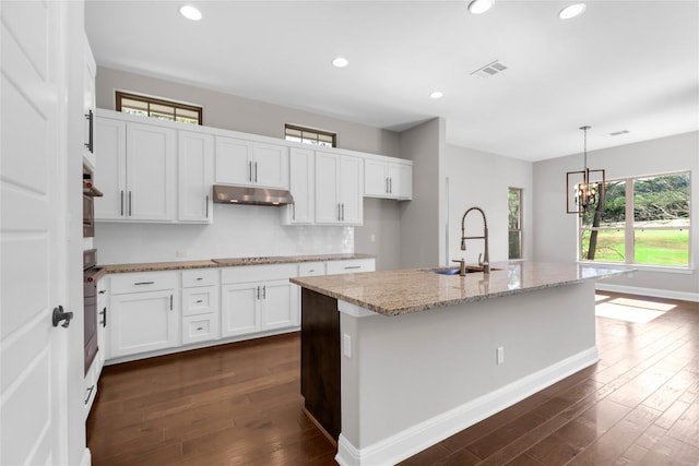 kitchen with a kitchen island with sink, sink, pendant lighting, dark hardwood / wood-style floors, and white cabinetry