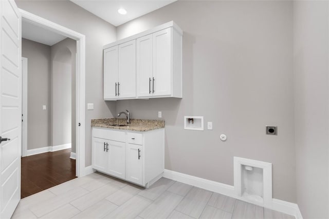 washroom featuring sink, cabinets, electric dryer hookup, light hardwood / wood-style flooring, and gas dryer hookup