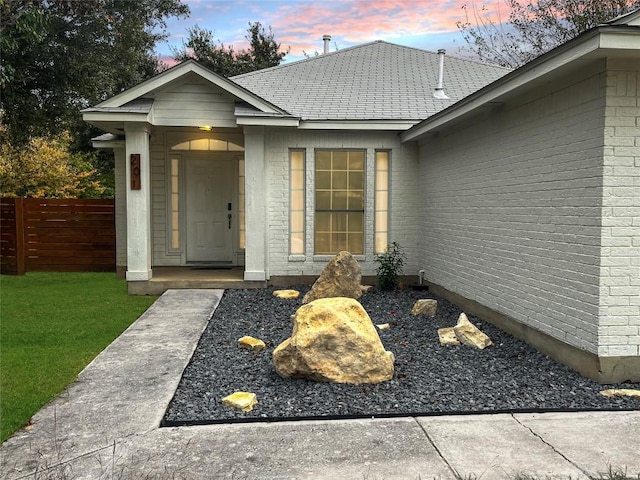 exterior entry at dusk featuring a lawn