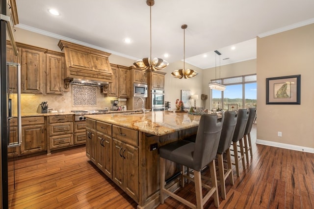 kitchen featuring decorative light fixtures, sink, backsplash, stainless steel appliances, and a spacious island