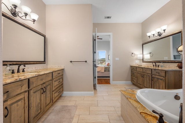 203 Serene Hilltop Cir, Lakeway, TX 78738 - full bathroom with two vanities, tiled tub, ensuite bathroom, and baseboards