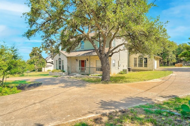 view of property hidden behind natural elements featuring a garage, covered porch, and a front lawn