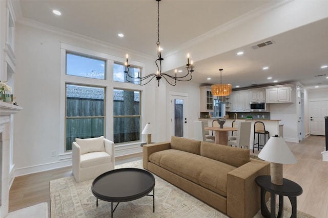 living room with light hardwood / wood-style floors, an inviting chandelier, and crown molding