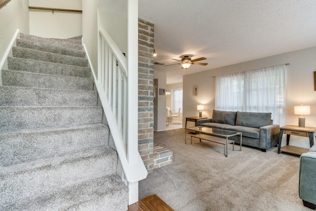 stairs with carpet flooring, ceiling fan, and a textured ceiling