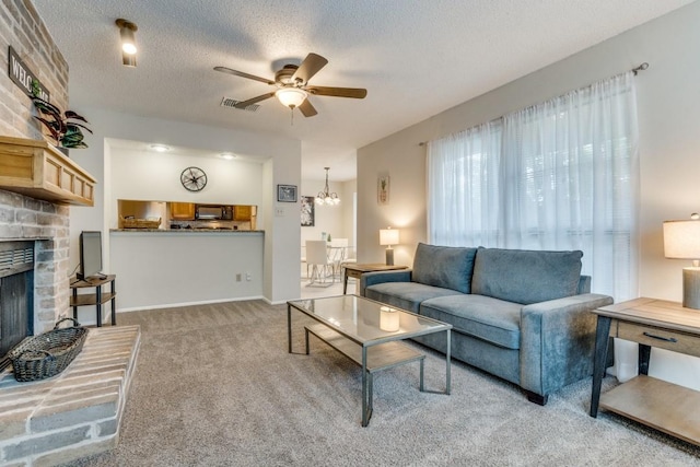 carpeted living room featuring ceiling fan with notable chandelier, a textured ceiling, and a brick fireplace