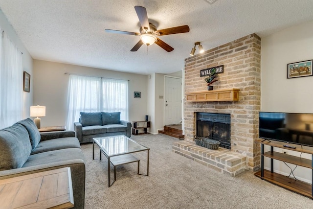 living room featuring ceiling fan, a fireplace, carpet floors, and a textured ceiling