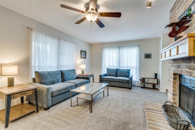 carpeted living room featuring a fireplace, ceiling fan, and a textured ceiling