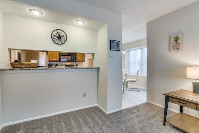 kitchen featuring stainless steel refrigerator, stone counters, light colored carpet, a textured ceiling, and decorative backsplash