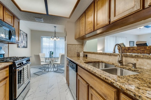 kitchen with backsplash, sink, appliances with stainless steel finishes, a notable chandelier, and light stone counters