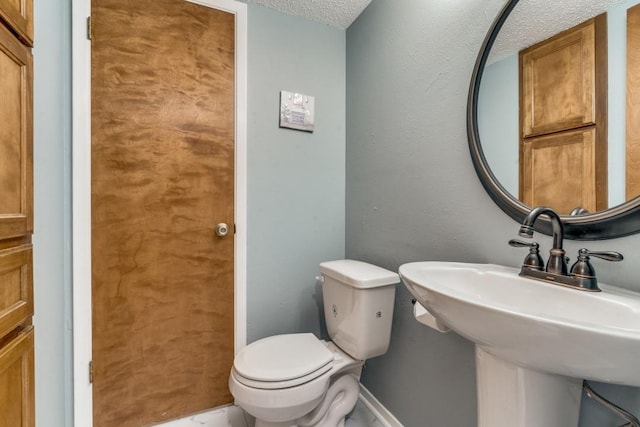 bathroom with a textured ceiling, toilet, and sink