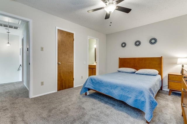 carpeted bedroom with a textured ceiling, ceiling fan, and ensuite bathroom