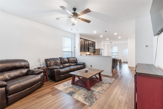 living room with ceiling fan, sink, and light hardwood / wood-style flooring