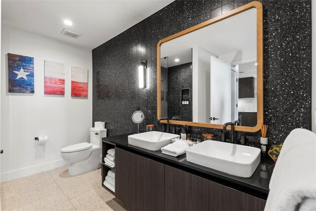 bathroom featuring vanity, toilet, and tile walls