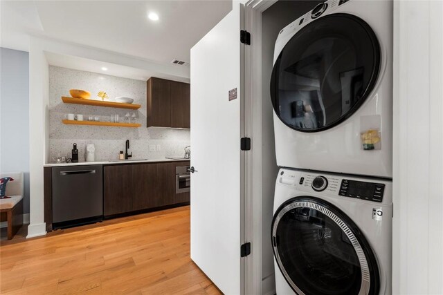 washroom with sink, stacked washer / dryer, and light hardwood / wood-style flooring