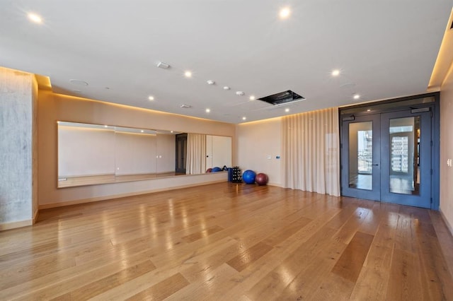 workout room with light hardwood / wood-style floors and french doors