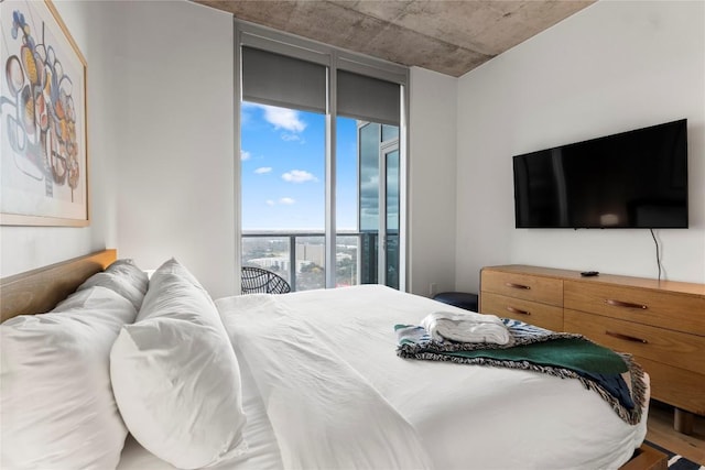 bedroom with floor to ceiling windows, access to exterior, and wood-type flooring