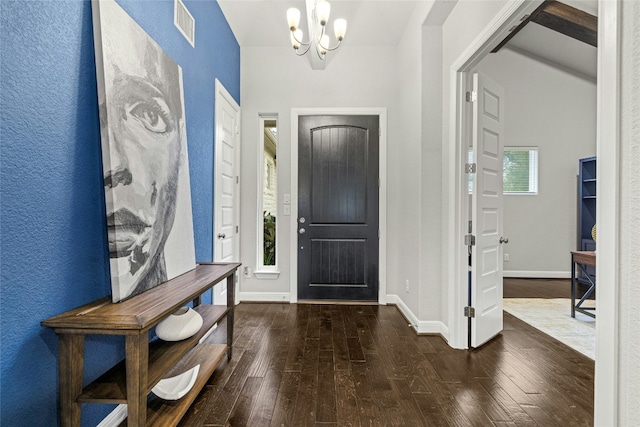 entryway with a wealth of natural light, dark wood-type flooring, and a notable chandelier