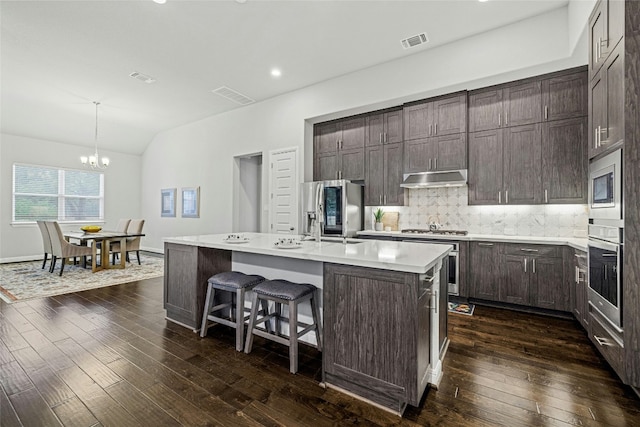 kitchen featuring a kitchen island with sink, hanging light fixtures, a notable chandelier, dark hardwood / wood-style flooring, and stainless steel appliances