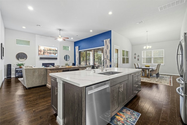 kitchen with a kitchen island with sink, sink, dark hardwood / wood-style floors, a fireplace, and appliances with stainless steel finishes