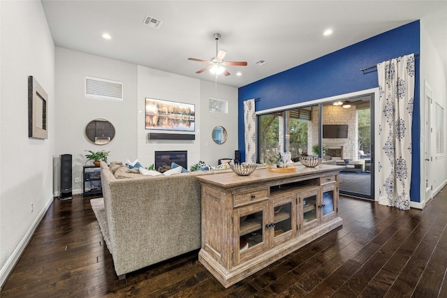 living room featuring dark hardwood / wood-style flooring, ceiling fan, and a fireplace