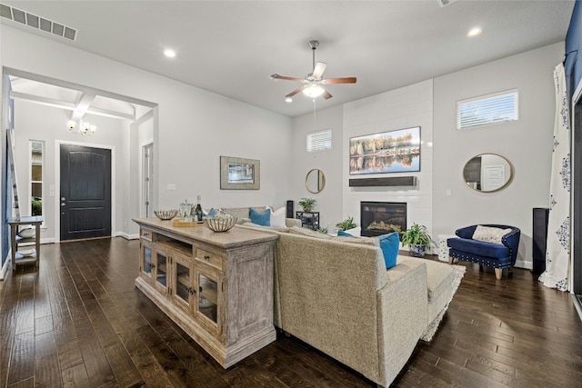 living room featuring a large fireplace, ceiling fan with notable chandelier, and dark hardwood / wood-style floors