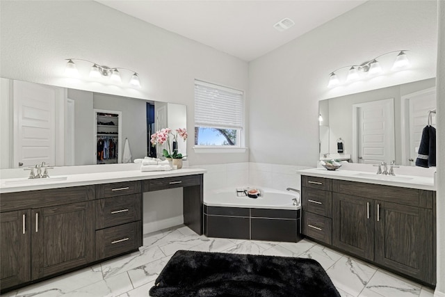 bathroom with vanity and tiled tub