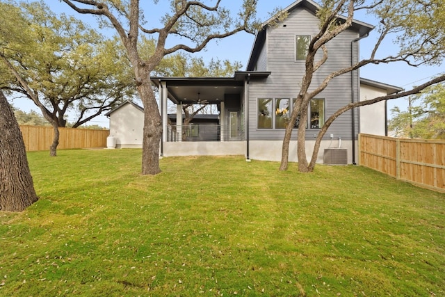 rear view of property with ceiling fan, cooling unit, and a lawn