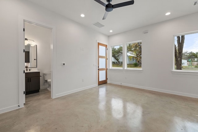 unfurnished bedroom with connected bathroom, multiple windows, and ceiling fan