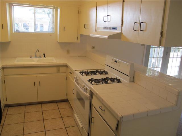 kitchen featuring white range with gas stovetop, sink, light tile patterned floors, kitchen peninsula, and extractor fan