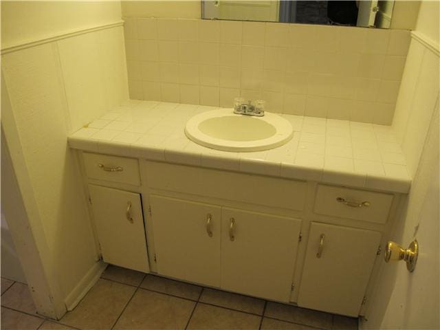 bathroom with tile patterned flooring, vanity, and tasteful backsplash