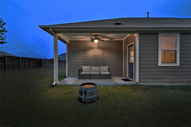 back house at dusk featuring a yard and ceiling fan