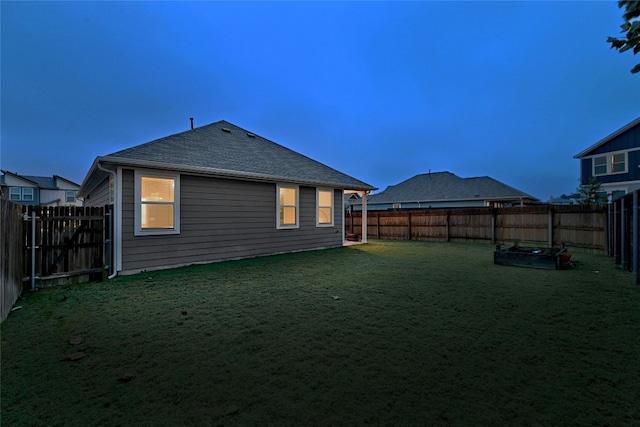 back house at dusk featuring a yard