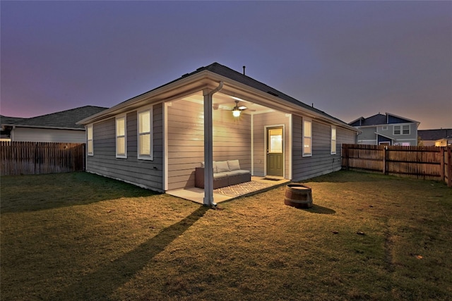 back house at dusk featuring a yard and ceiling fan