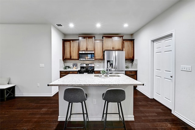 kitchen with decorative backsplash, dark hardwood / wood-style flooring, an island with sink, and stainless steel appliances