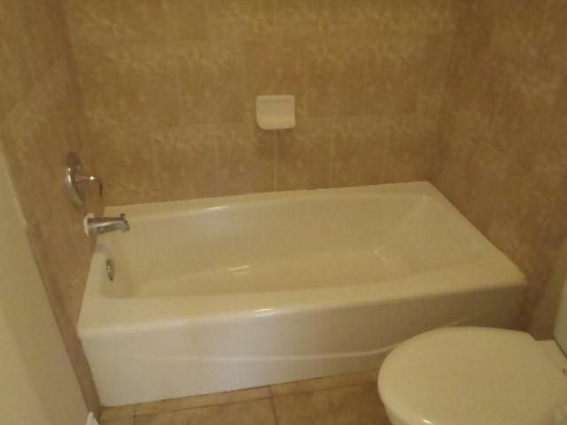 bathroom featuring tile patterned flooring, toilet, and a bathing tub