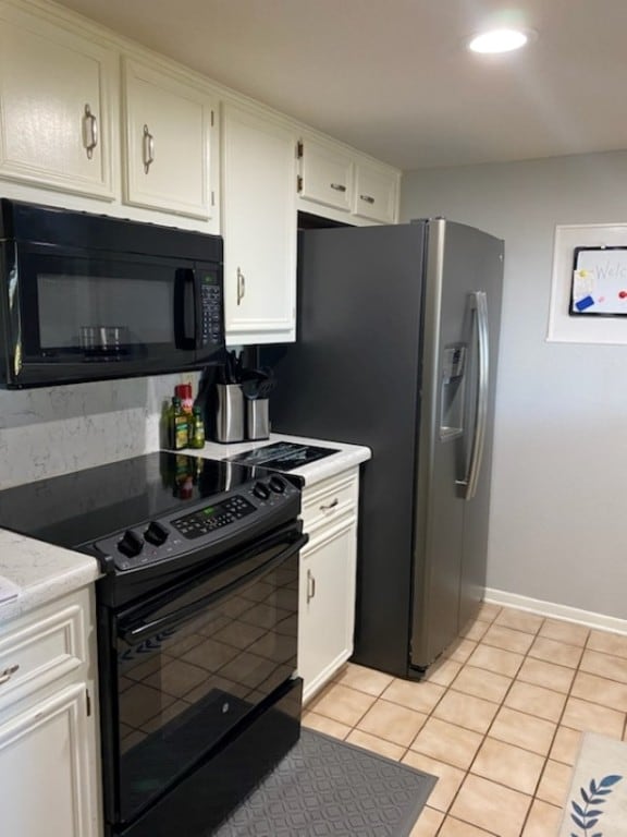 kitchen with white cabinets, black appliances, and light tile patterned floors