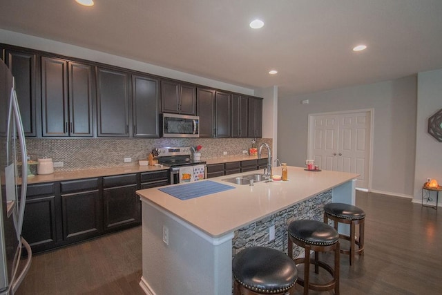 kitchen with appliances with stainless steel finishes, sink, dark hardwood / wood-style flooring, and an island with sink