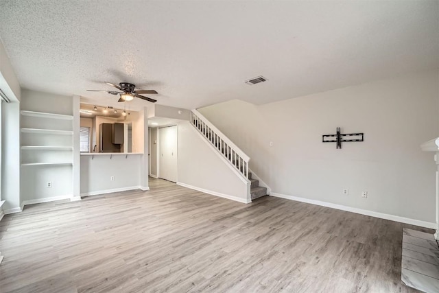 unfurnished living room with hardwood / wood-style flooring, ceiling fan, and a textured ceiling