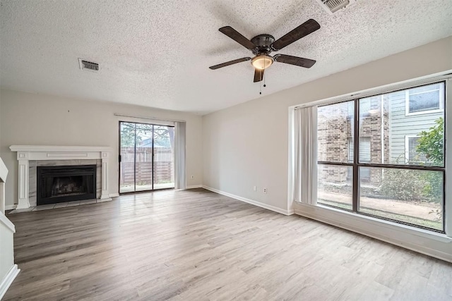 unfurnished living room featuring a tile fireplace, wood-type flooring, and a textured ceiling