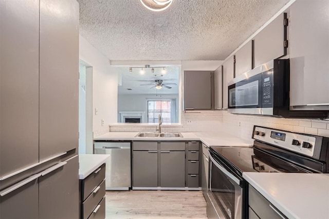 kitchen featuring decorative backsplash, sink, stainless steel appliances, and light wood-type flooring