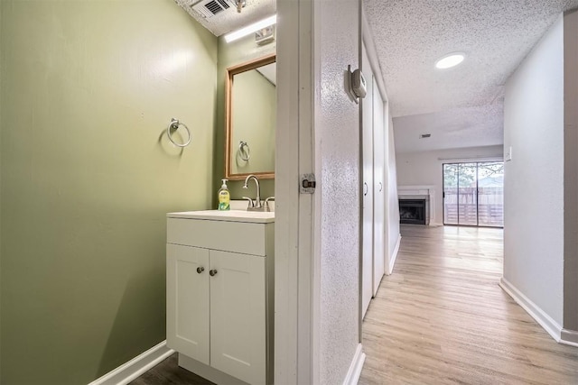 bathroom with hardwood / wood-style floors, vanity, and a textured ceiling