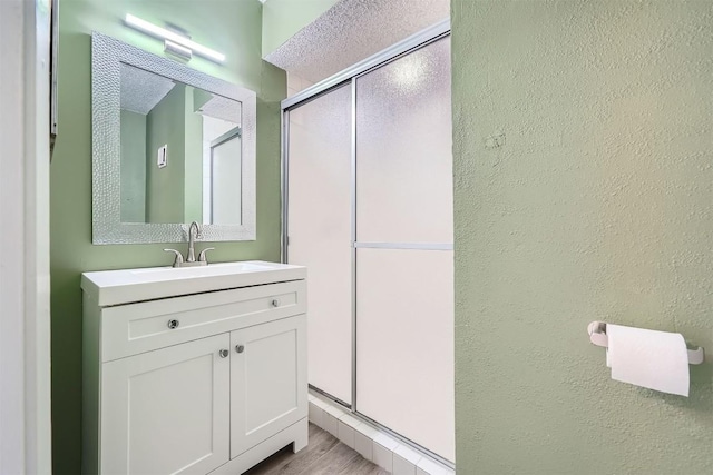 bathroom featuring a textured ceiling, vanity, hardwood / wood-style flooring, and a shower with shower door