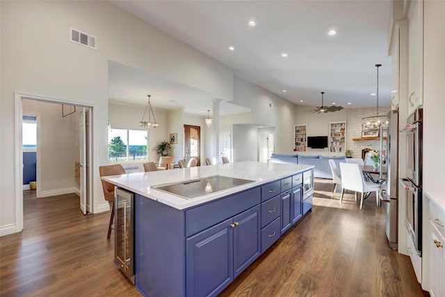 kitchen with ceiling fan, blue cabinets, a breakfast bar area, a kitchen island with sink, and appliances with stainless steel finishes