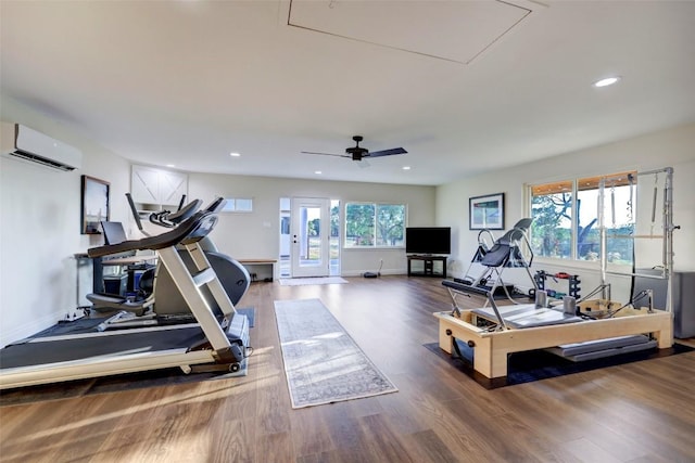 exercise room featuring an AC wall unit, ceiling fan, and hardwood / wood-style floors