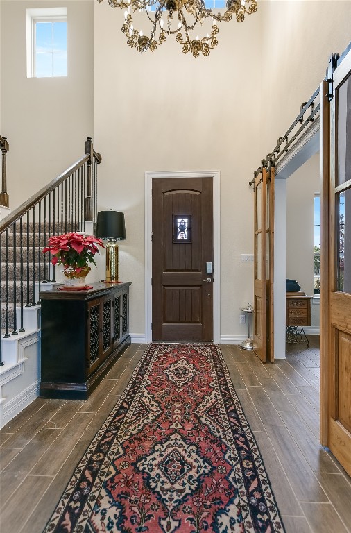 foyer entrance featuring a towering ceiling, a barn door, dark hardwood / wood-style floors, and a wealth of natural light