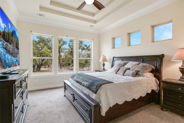 bedroom featuring ceiling fan, light colored carpet, crown molding, and a tray ceiling