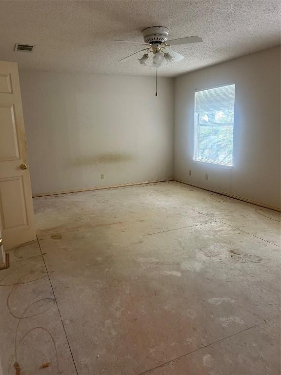 unfurnished room with ceiling fan and a textured ceiling