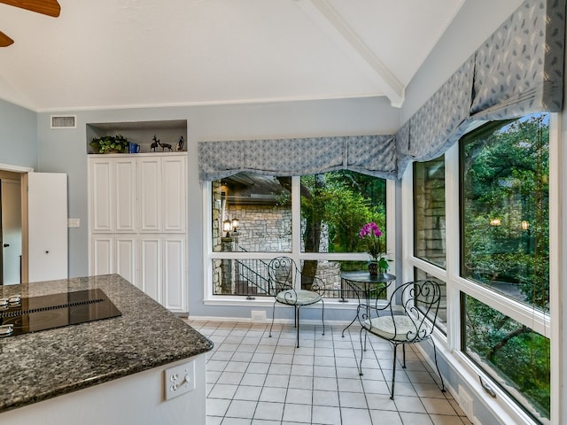 3901 Prentice Ln, Austin, TX 78746 - kitchen featuring black electric stovetop, light tile patterned floors, ceiling fan, dark stone counters, and healthy amount of natural light