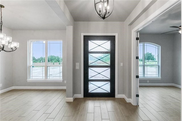 entrance foyer featuring ceiling fan with notable chandelier, a healthy amount of sunlight, and light hardwood / wood-style flooring