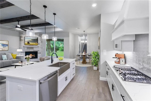 kitchen featuring premium range hood, sink, hanging light fixtures, stainless steel appliances, and white cabinets